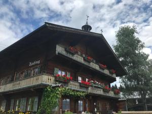 a building with a balcony with red flowers on it at Bergpension Zinting in Brixen im Thale