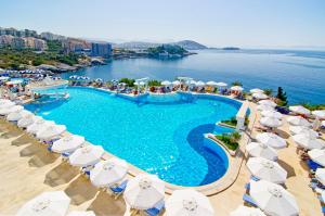 an image of a swimming pool with umbrellas and the ocean at Korumar Hotel Deluxe in Kuşadası