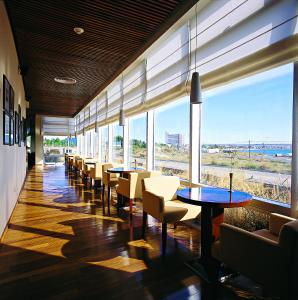 a restaurant with tables and chairs and a view of the beach at Hotel Territorio in Puerto Madryn