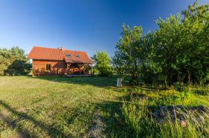 a house with a red roof in a field at Domek na Górce in Sorkwity