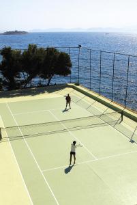 
two people playing tennis on a tennis court at Korumar Hotel Deluxe in Kuşadası
