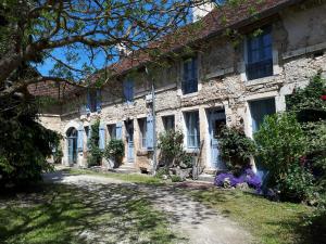 an old stone house with blue windows and purple flowers at La Cour in Flavigny-sur-Ozerain