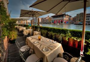 a row of tables and umbrellas on a patio next to a river at Ca' Sagredo Hotel in Venice