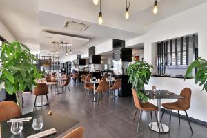 un restaurante con mesas, sillas y plantas en Hotel & Restaurant Perla Riviera, en Villeneuve-Loubet