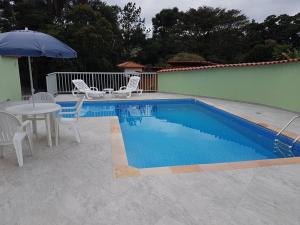 a swimming pool with a table and chairs and an umbrella at Pousada Vila Cocais in Cocais