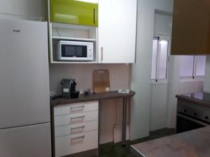 a small kitchen with white cabinets and a microwave at La casa de Blanca. Coqueto piso céntrico y cerca de todo in Almería