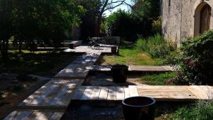 a garden with a wooden pathway with benches and trees at Le clos des abeilles in Ruch