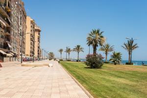 a street with palm trees and the ocean in the background at ApartUP Saplaya Harbour in Alboraya