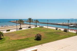 a park next to the beach with palm trees and the ocean at ApartUP Saplaya Harbour in Alboraya