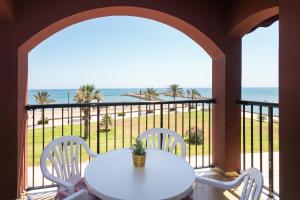 a white table and chairs on a balcony with the ocean at ApartUP Saplaya Harbour in Alboraya