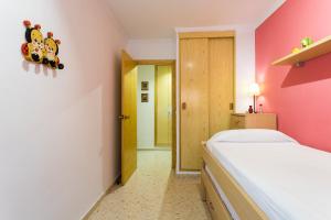a bedroom with a white bed and a pink wall at ApartUP Saplaya Harbour in Alboraya