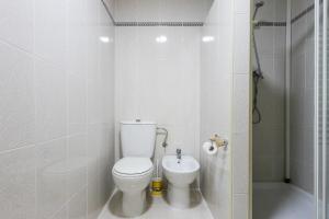 a white bathroom with a toilet and a shower at ApartUP Saplaya Harbour in Alboraya