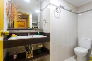 a bathroom with a sink and a toilet and a mirror at ApartUP Saplaya Harbour in Alboraya