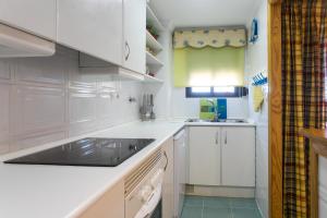 a white kitchen with white cabinets and a sink at ApartUP Saplaya Harbour in Alboraya
