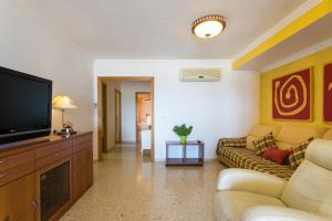a living room with a couch and a television at ApartUP Saplaya Harbour in Alboraya