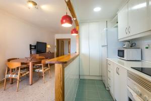 a kitchen with a wooden table and a kitchen with a dining room at ApartUP Saplaya Harbour in Alboraya