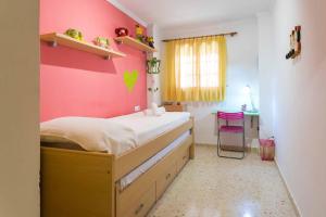 a bedroom with a bed with a pink wall at ApartUP Saplaya Harbour in Alboraya