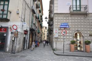 un gruppo di persone che camminano per una strada con edifici di GuestHost - Dimora del Barone a Salerno