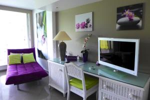uma sala de estar com uma secretária, uma televisão e um sofá roxo em Résidence de La Vieille Tour em Le Gosier