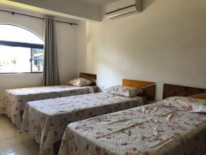 3 camas en una habitación con ventana en Pousada do Coqueiro, en Urubici