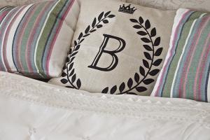 B&B Buggenum Palace في Buggenum: وسادة مكتوب عليها حرف ب تجلس على سرير