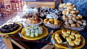 a table filled with different types of bread and pastries at Pousada dos Esquilos in Campos do Jordão