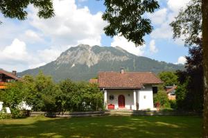 ein kleines weißes Haus mit einem Berg im Hintergrund in der Unterkunft Haus Iris in Oberstdorf
