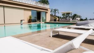 una piscina con 2 sillas blancas junto a una casa en Tenuta Mara Wine Relais, en San Clemente