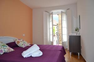 a bedroom with a purple bed with towels on it at Albergue Valle del Nonaya in Salas