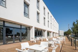 a deck with white tables and chairs on a building at V&aacute;rda Sport Hotel in Kisv&aacute;rda