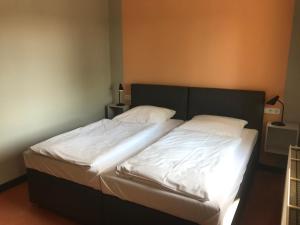 Schlafzimmer mit einem Bett mit weißer Bettwäsche in der Unterkunft Hotel Kipphut in Sarstedt