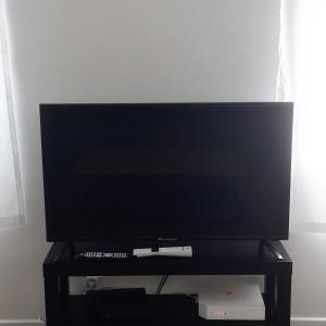 a flat screen tv sitting on a black stand at Maison enti&egrave;re au pied des vignes in Lussac