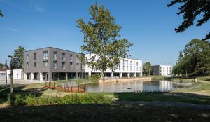 a building with a pond in front of a building at V&aacute;rda Sport Hotel in Kisv&aacute;rda