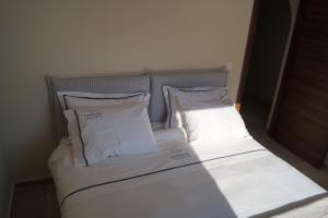 Una cama con sábanas blancas y almohadas en una habitación. en Lagkada Suites, en Kariá