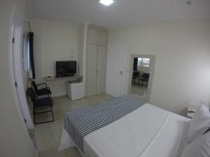 a white bedroom with a bed and a television at Dumont Park Hotel in Sao Jose do Rio Preto