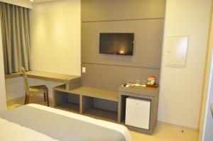 Marechal Cândido RondonにあるHospedare Hotelのベッド、デスク、テレビが備わるホテルルームです。