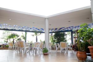 a patio with white tables and chairs and palm trees at Hotel Rodon in Paralia Katerinis