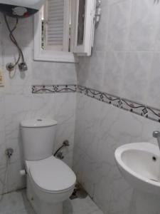 a white bathroom with a toilet and a sink at R1 CH21 studio 2 beds poolside garden terrace Green Beach in El Alamein
