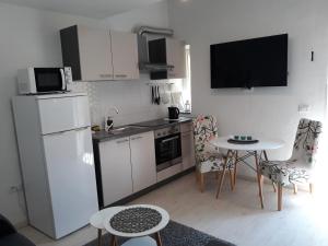 a kitchen with a white refrigerator and a table with chairs at Dajven in Pula