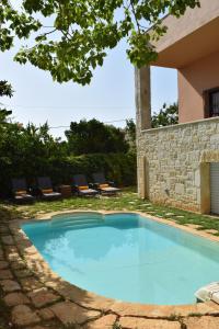 una piscina en un patio con sillas y árboles en Villa Avly en Maleme