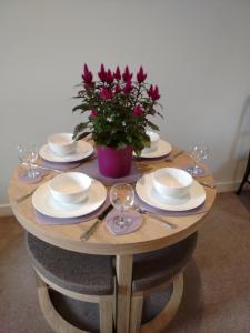 a wooden table with plates and glasses and a potted plant at Strachan House in Inverkeithing