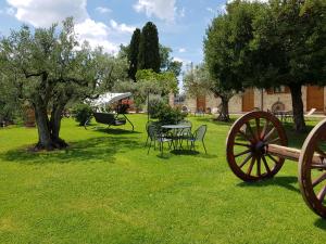 einen Garten mit einem Tisch, Stühlen und Bäumen in der Unterkunft Agriturismo Arcobaleno della Torretta in Giano dellʼUmbria
