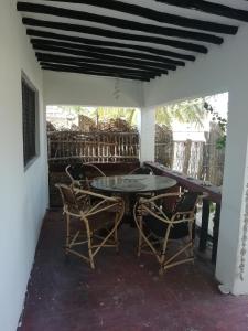 patio con tavolo e sedie sotto il portico di Sunny House Paje II a Paje