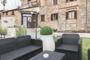 eine Terrasse mit 2 Stühlen, einem Tisch und einem Gebäude in der Unterkunft Hotel Le Macine in Montaione