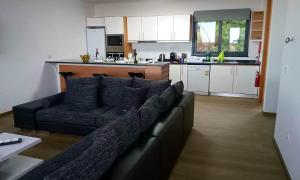 a living room with a couch and a kitchen at migs'place in Arco da Calheta