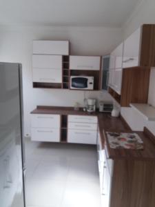 una pequeña cocina con armarios blancos y microondas en Residencial Castelo Branco, en Campinas