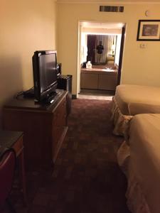 una habitación de hotel con TV en un tocador y un dormitorio en Cheshire Motor Inn en Atlanta