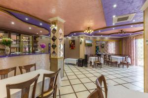een restaurant met witte tafels en stoelen en paarse plafonds bij Guest House Viva Viktoria in Novorossiejsk