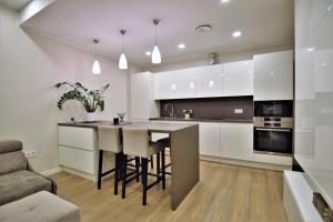 a kitchen with white cabinets and a island with bar stools at Europa Dream Apartment in Vilnius