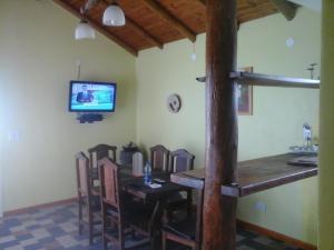 Un comedor con mesa y sillas y un televisor. en Sierra Magenta, en Los Hornillos